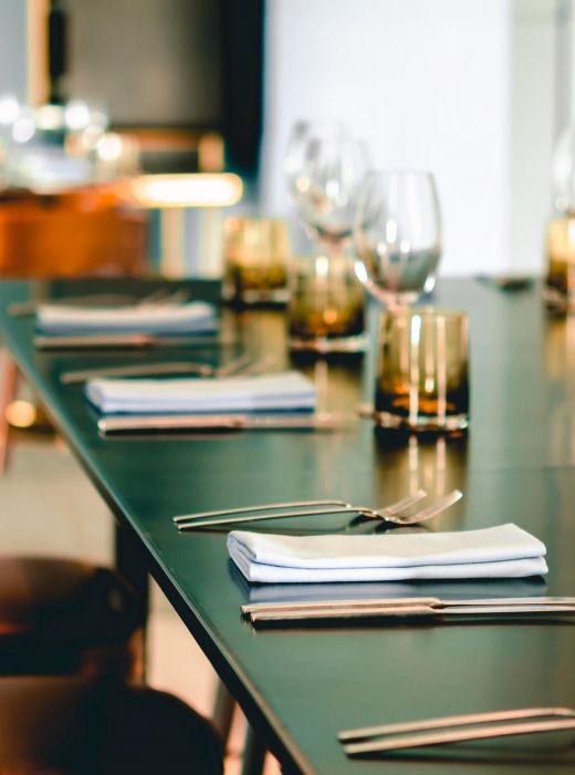 Elegant table set with wine glasses, water glasses, cutlery, and napkins in a modern restaurant setting.